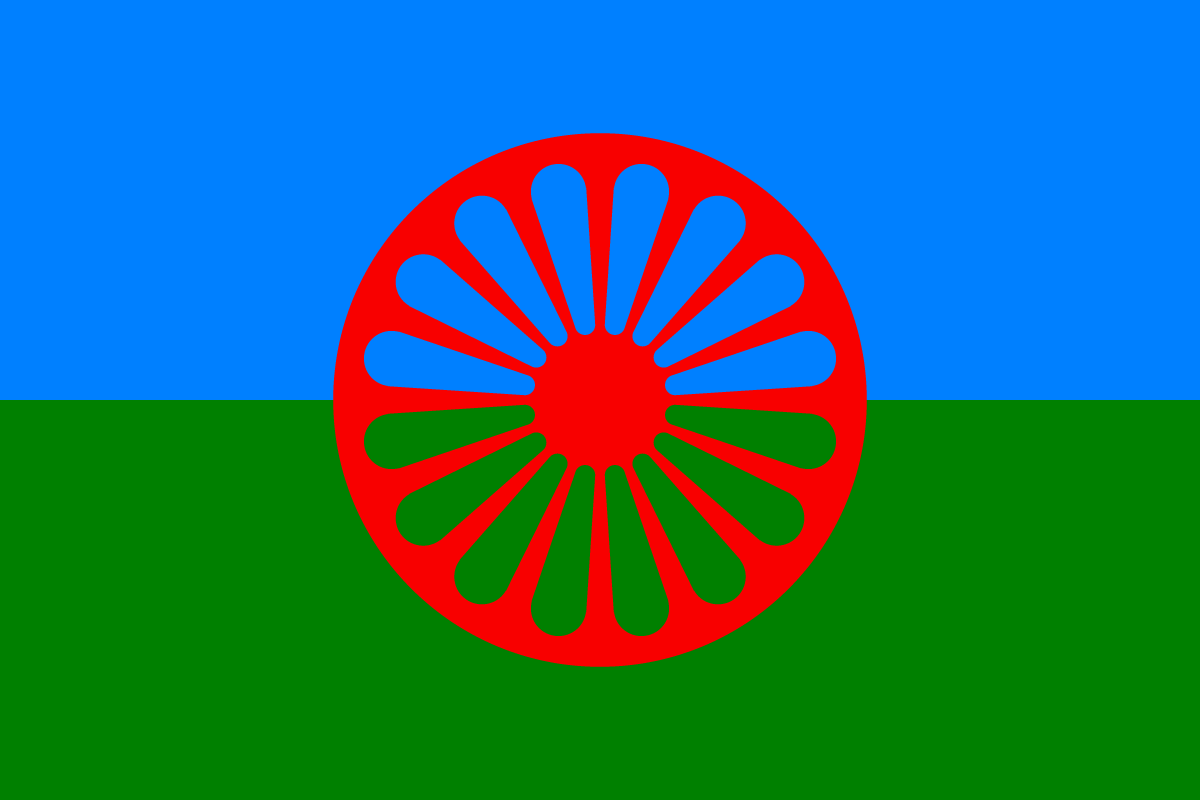 Det romske flagget, et rødt, eikete hjul på en horisontalt delt grønn og blå bakgrunn.