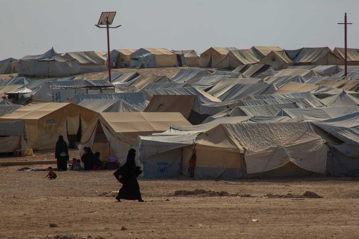 Telt i teltleir i Syria, kvinne i burka går foran teltene.