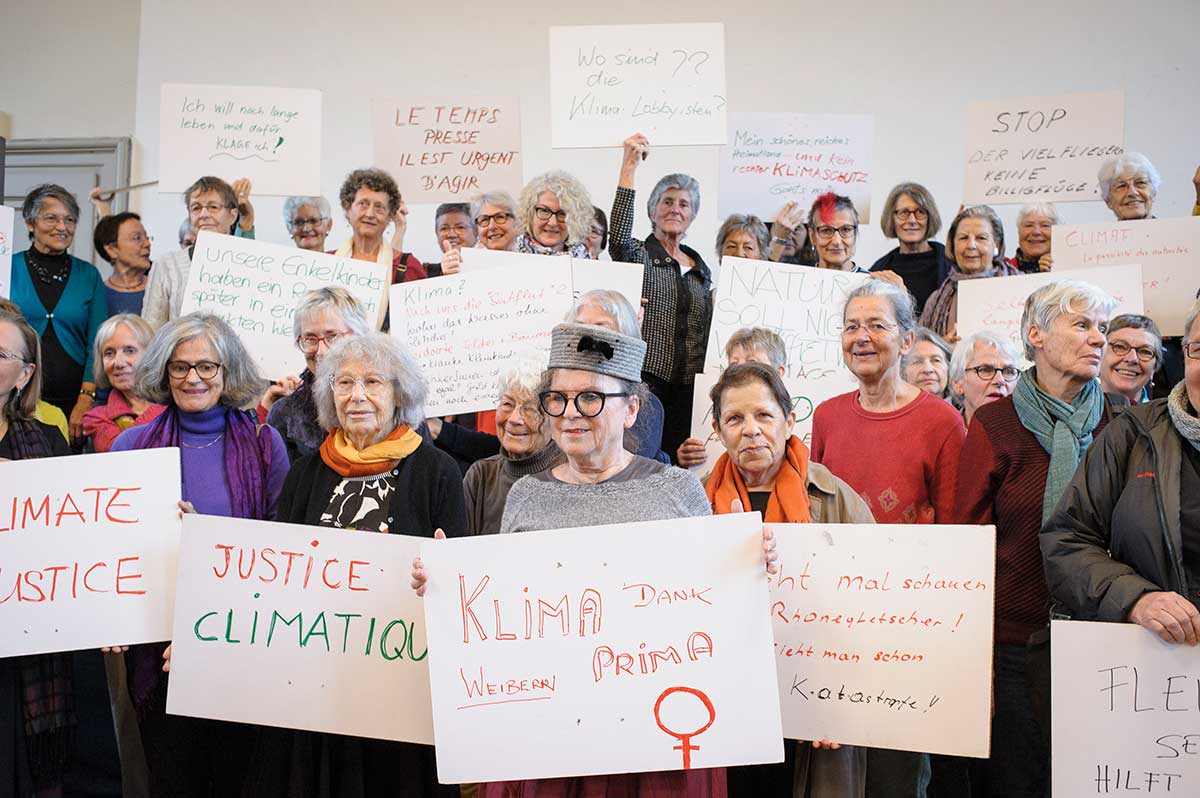 En samling eldre kvinner som holder plakater med apeller om klimatiltak