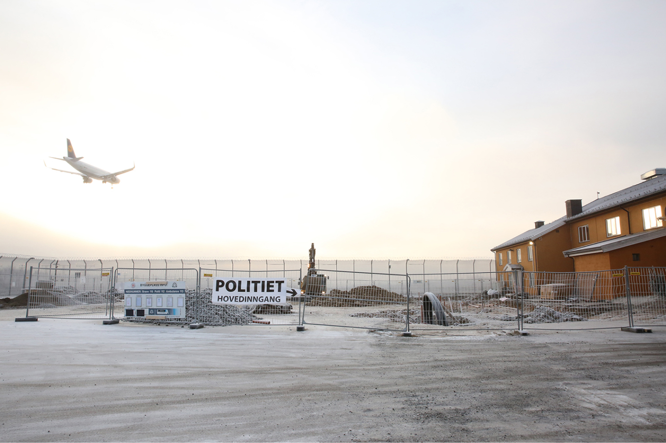 Utlendingsinternatet på Trandum i klart vintervær, et passasjerfly kan sees i bakgrunnen.